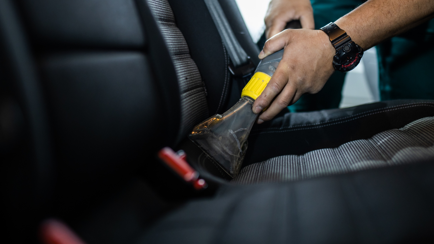 A person cleaning a car seat with a cloth